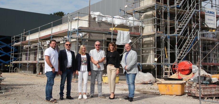 Auf dem Bild sehen Sie 6 Personen vor dem Bau eines neuen Unternehmensgebäude des Unternehmen Dreier Moden GmbH. von links nach rechts, Dennis Heinrichs (Projektleiter Ingenierbüro Hoff und Partner), Theo Dreier (Unternehmensgründer), Cathrin Dreier-Althaus (Geschäftsführerin), Bernd Niehoff (Architekt Hoff und Partner), Katharina Vater (Geschäftsführung Wirtschaftsförderung) und Rainer Reimer (stellv. Vorsitzender des Aufsichtsrates der Wirtschaftsförderung).